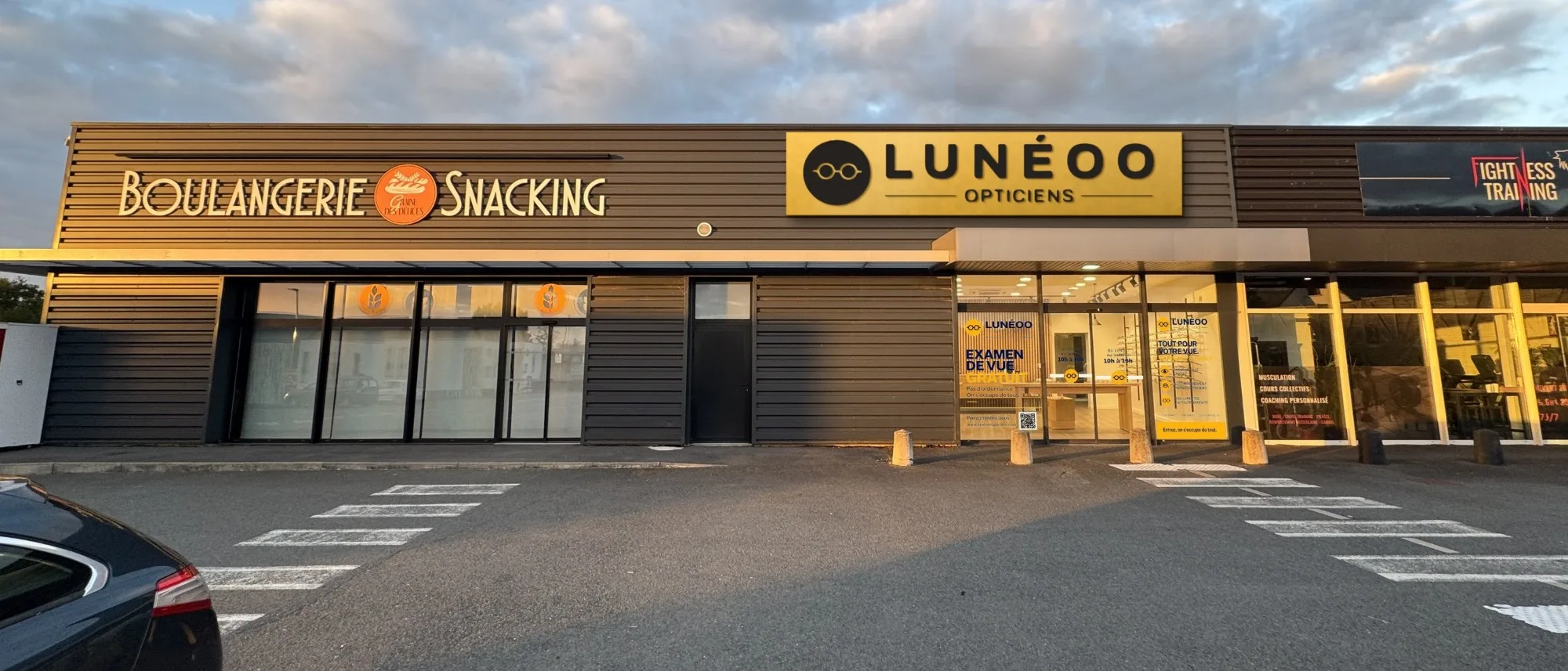 Devanture de Lunéoo Opticiens à Montauban-de-Bretagne, entre la boulangerie et la salle de sport, avec le parking devant la boutique