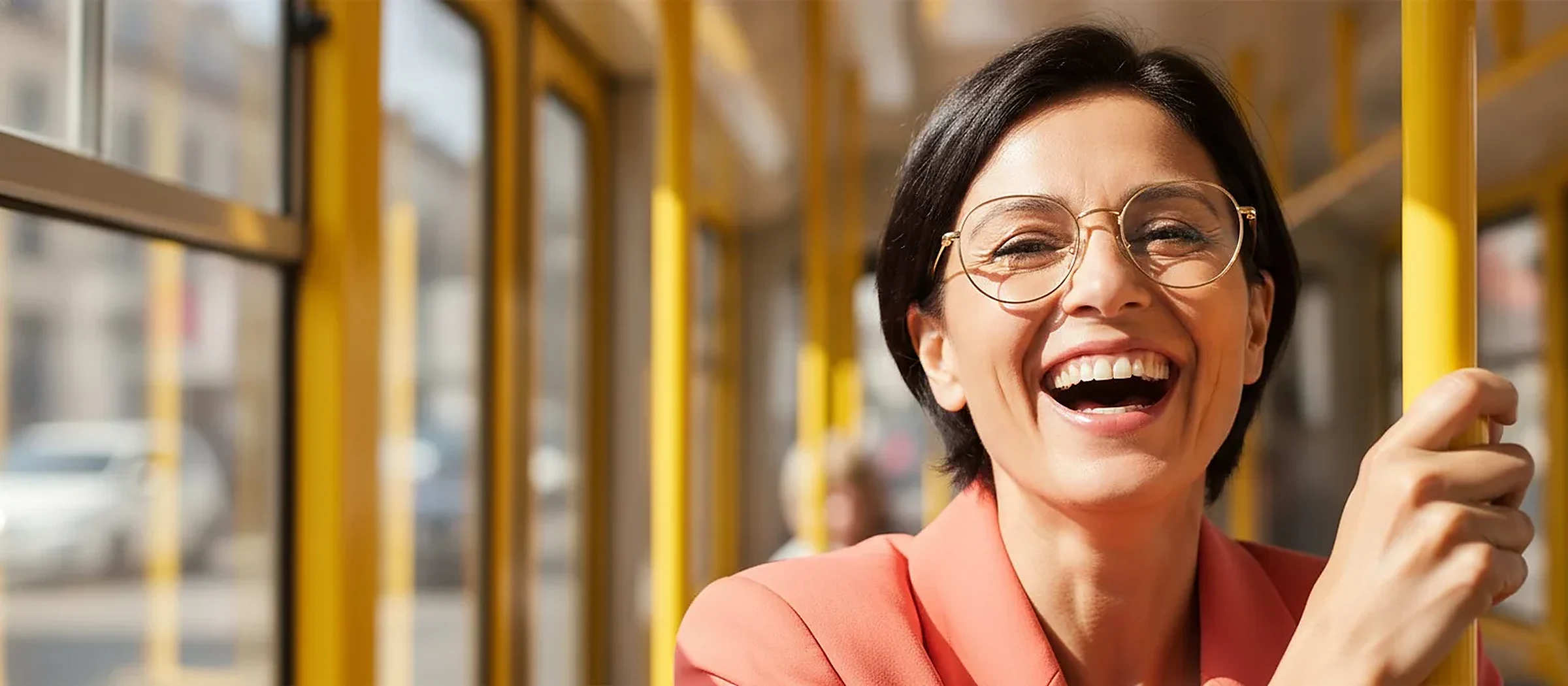 Femme riant portant des lunettes rondes dorées, dans un tramway
